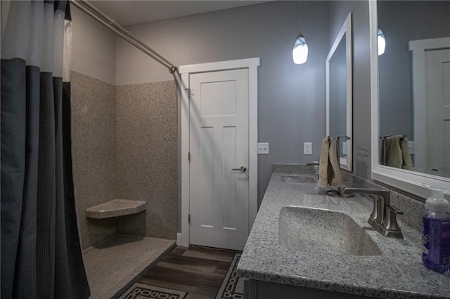full bath with double vanity, curtained shower, wood finished floors, and a sink
