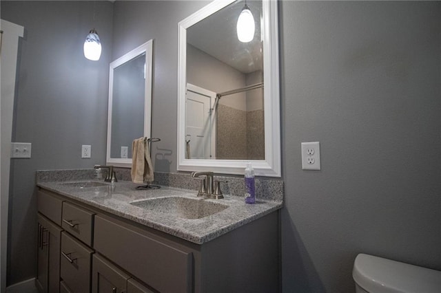 bathroom with a sink, double vanity, and toilet