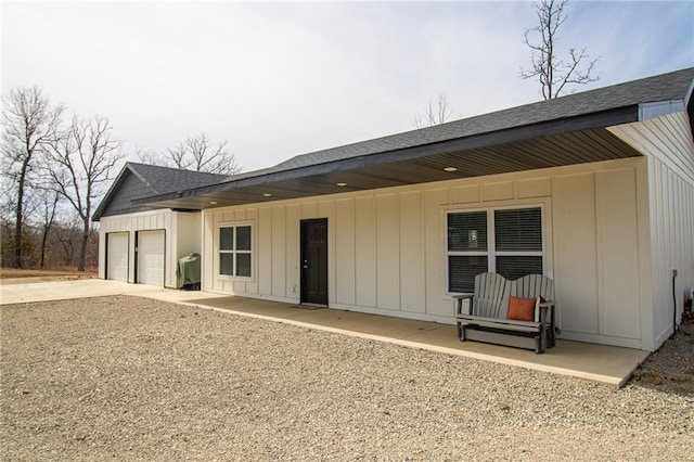 back of property featuring roof with shingles, concrete driveway, an attached garage, and board and batten siding