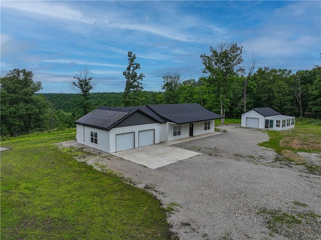 3813 Mt Horeb Rd, Camdenton, MO 65020 - ranch-style house with solar panels, a view of trees, a front yard, and an outdoor structure