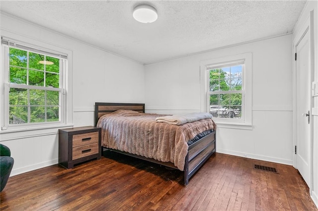 5801 E 56th St, Kansas City, MO 64129 - bedroom with a decorative wall, dark wood-style flooring, and a textured ceiling