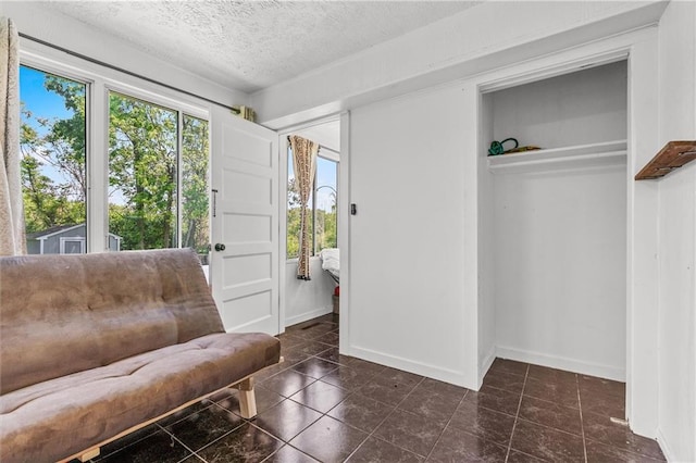 5801 E 56th St, Kansas City, MO 64129 - living area with dark tile patterned flooring, baseboards, and a textured ceiling