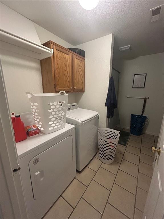 722 N Virginia St, Adrian, MO 64720 - washroom with separate washer and dryer, light tile patterned floors, cabinet space, and a textured ceiling