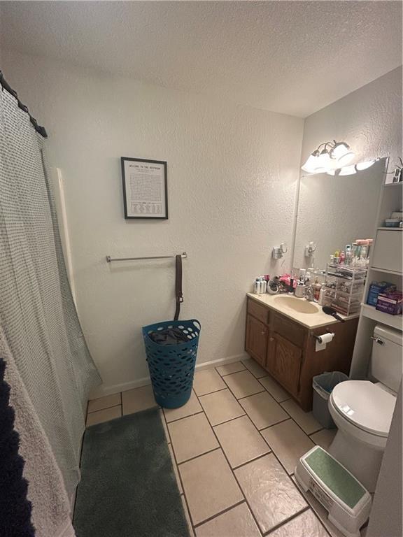 722 N Virginia St, Adrian, MO 64720 - full bath featuring tile patterned flooring, a textured ceiling, toilet, vanity, and a textured wall