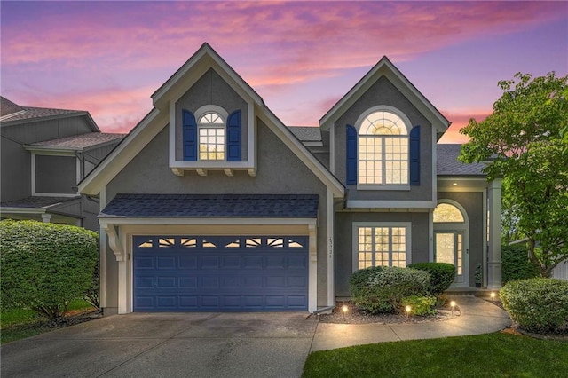 traditional-style house featuring concrete driveway, stucco siding, and a garage