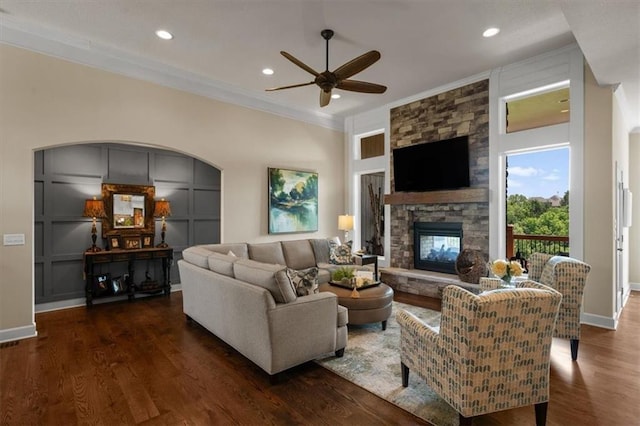 living room with a ceiling fan, a stone fireplace, dark wood-type flooring, baseboards, and recessed lighting