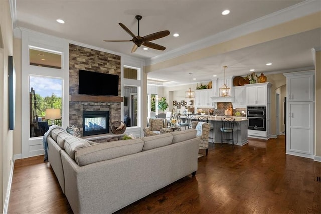 living room with a fireplace, ornamental molding, ceiling fan, plenty of natural light, and dark wood-style floors