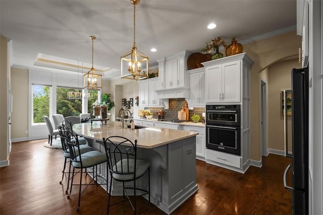 kitchen with a sink, tasteful backsplash, baseboards, a chandelier, and ornamental molding