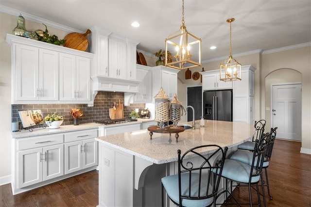 kitchen featuring high quality fridge, a sink, white cabinetry, a chandelier, and ornamental molding
