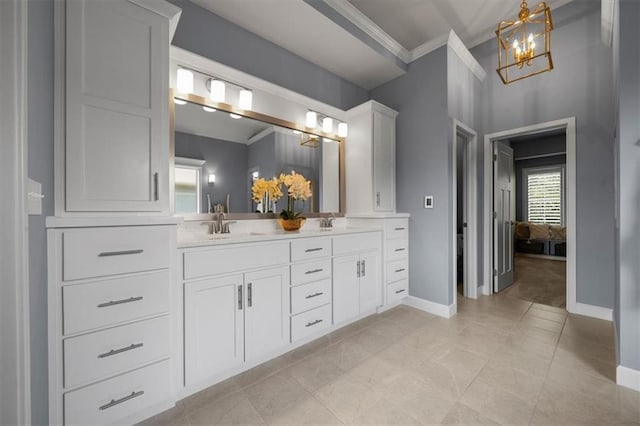 bathroom featuring a chandelier, crown molding, baseboards, and double vanity