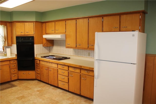 kitchen featuring under cabinet range hood, light countertops, brown cabinets, and black appliances