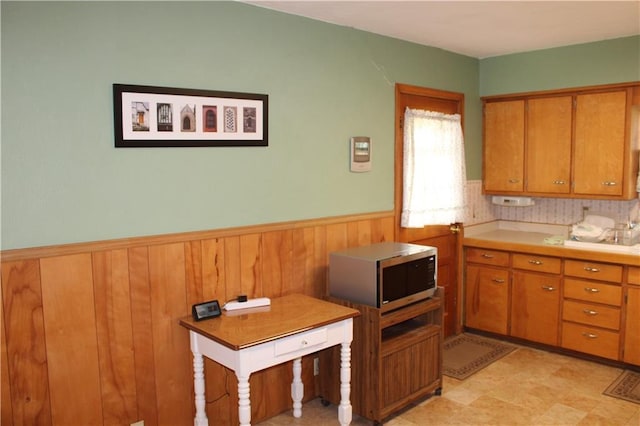 kitchen with brown cabinets, wainscoting, and stainless steel microwave