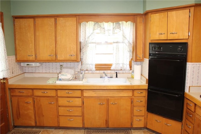 kitchen with dobule oven black, light countertops, and brown cabinetry
