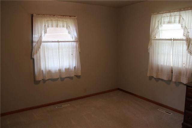 empty room featuring visible vents, baseboards, and light carpet