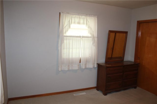unfurnished bedroom with baseboards, light carpet, and visible vents