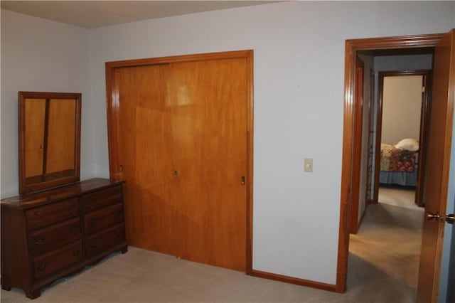 bedroom with baseboards, a closet, and light colored carpet