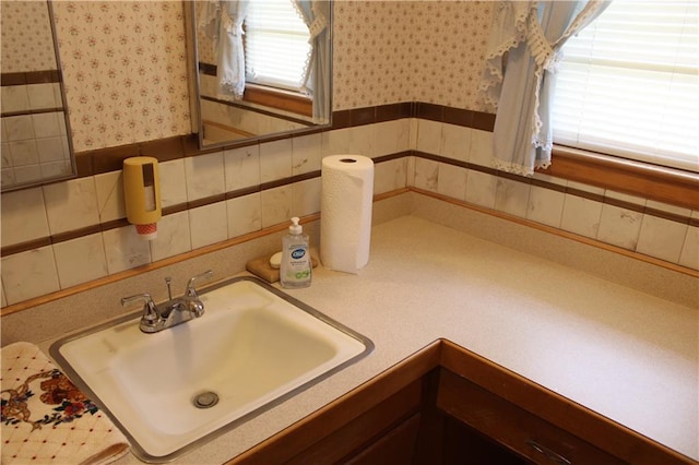 bathroom featuring wallpapered walls, vanity, and wainscoting
