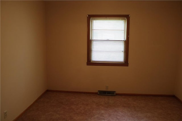 carpeted empty room featuring plenty of natural light, visible vents, and baseboards