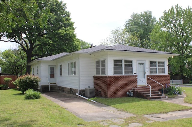 view of front facade featuring entry steps, cooling unit, and a front yard