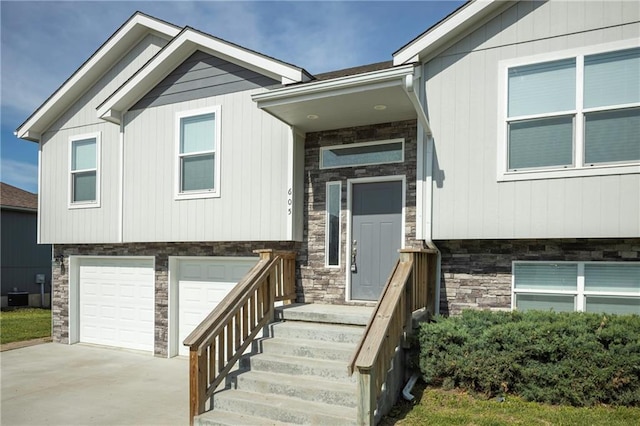 605 Carr St, Knob Noster, MO 65336 - view of front facade featuring stone siding, an attached garage, driveway, and central air condition unit