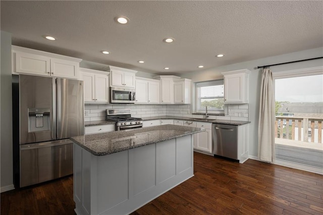 605 Carr St, Knob Noster, MO 65336 - kitchen featuring stainless steel appliances, white cabinets, a kitchen island, tasteful backsplash, and a textured ceiling