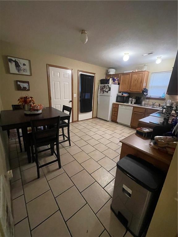 kitchen with white appliances, light tile patterned flooring, and brown cabinets