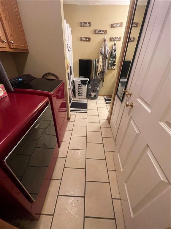 washroom with cabinet space, washing machine and clothes dryer, and light tile patterned floors