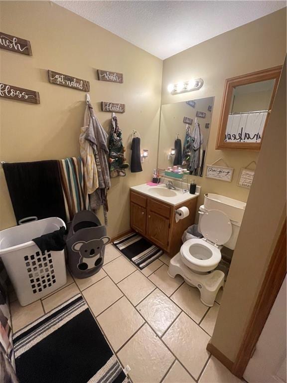 full bathroom featuring toilet, tile patterned floors, vanity, and a textured ceiling
