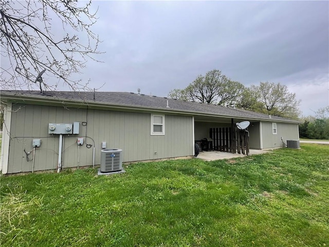 rear view of property with cooling unit, a yard, and a patio