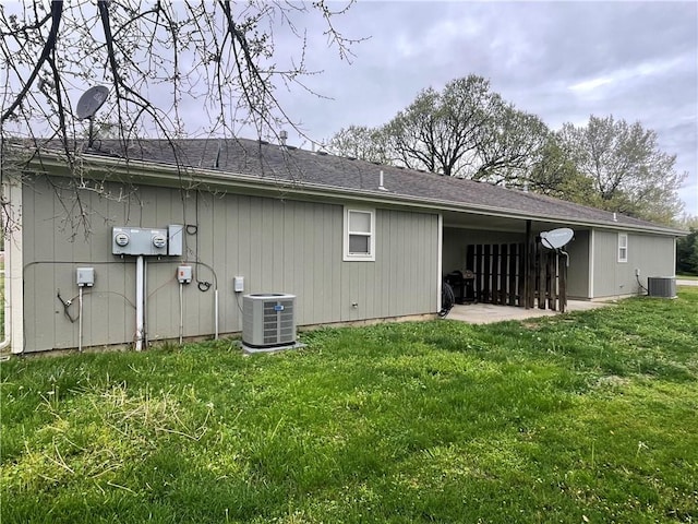 rear view of house featuring central AC unit and a yard