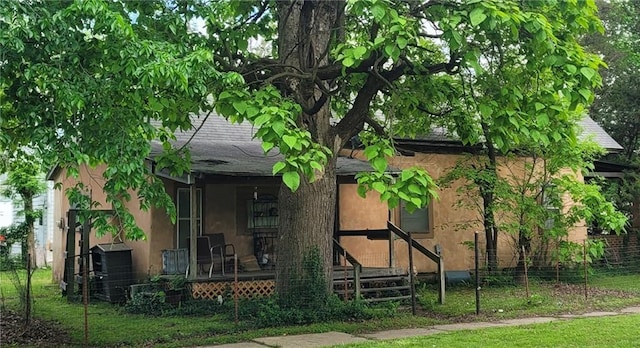 view of property exterior featuring a lawn, central air condition unit, a porch, and stucco siding