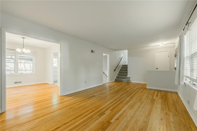 5707 W 101st Ter, Overland Park, KS 66207 - unfurnished living room with a chandelier, stairs, light wood finished floors, and baseboards