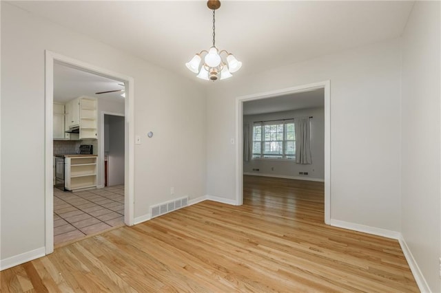 5707 W 101st Ter, Overland Park, KS 66207 - spare room featuring a chandelier, light wood-style floors, and baseboards