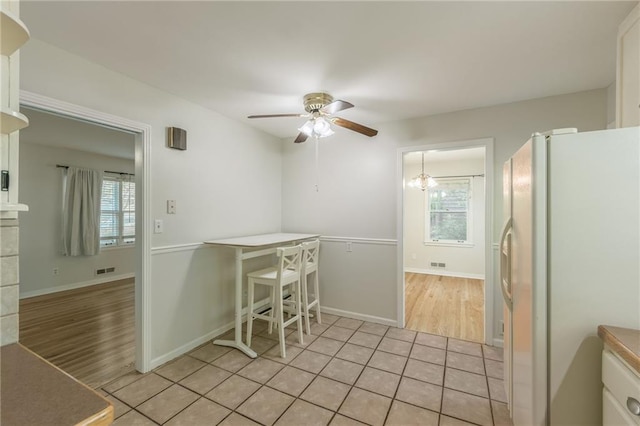 5707 W 101st Ter, Overland Park, KS 66207 - kitchen with white refrigerator with ice dispenser, a ceiling fan, healthy amount of natural light, and light tile patterned floors
