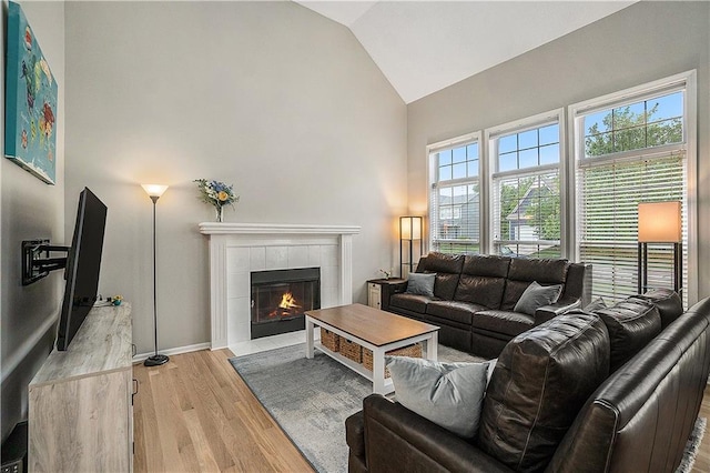 15951 S Avalon St, Olathe, KS 66062 - living area with light wood-style flooring, high vaulted ceiling, a tile fireplace, and baseboards