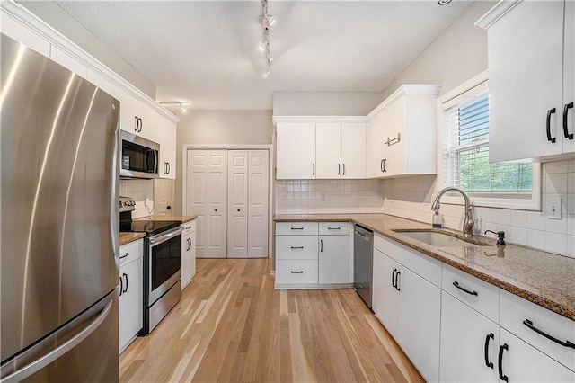15951 S Avalon St, Olathe, KS 66062 - kitchen with appliances with stainless steel finishes, a sink, tasteful backsplash, light wood-style flooring, and white cabinetry