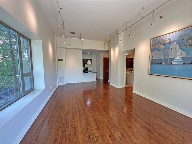 4950 Central St Unit 102, Kansas City, MO 64112 - unfurnished living room with rail lighting, dark wood-style floors, a high ceiling, and baseboards