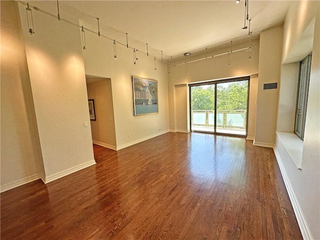 4950 Central St Unit 102, Kansas City, MO 64112 - unfurnished room featuring a high ceiling, dark wood-type flooring, baseboards, and track lighting