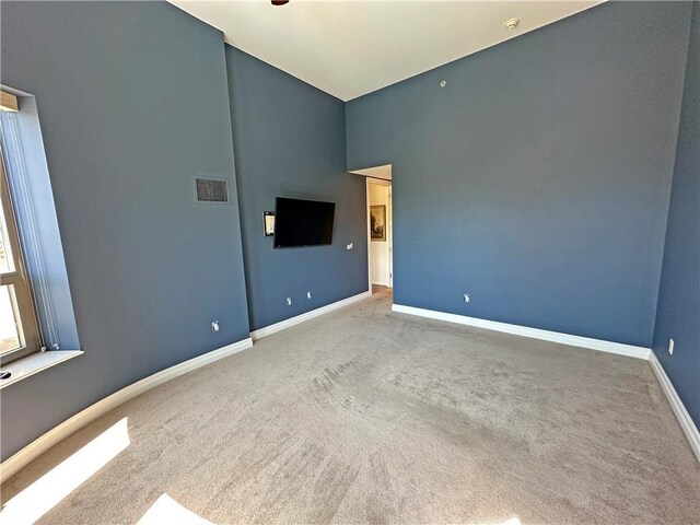 4950 Central St Unit 102, Kansas City, MO 64112 - spare room featuring carpet flooring, baseboards, and a towering ceiling