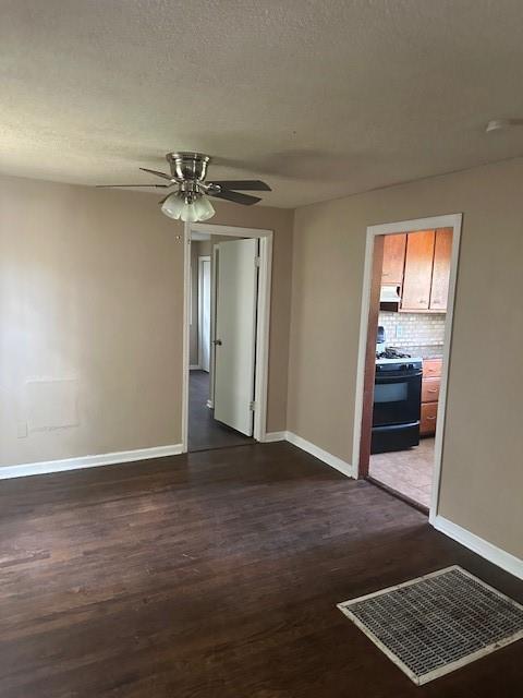 3805 Laurel Ave, Kansas City, MO 64133 - unfurnished room with baseboards, dark wood-style flooring, visible vents, and a ceiling fan