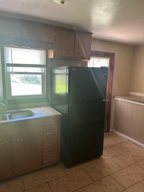 3805 Laurel Ave, Kansas City, MO 64133 - kitchen with freestanding refrigerator, light countertops, light tile patterned floors, and a sink