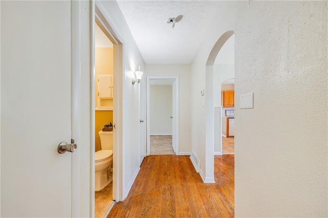 6132 N Eugene Field Rd, Kansas City, MO 64119 - corridor featuring arched walkways, wood finished floors, baseboards, and a textured ceiling