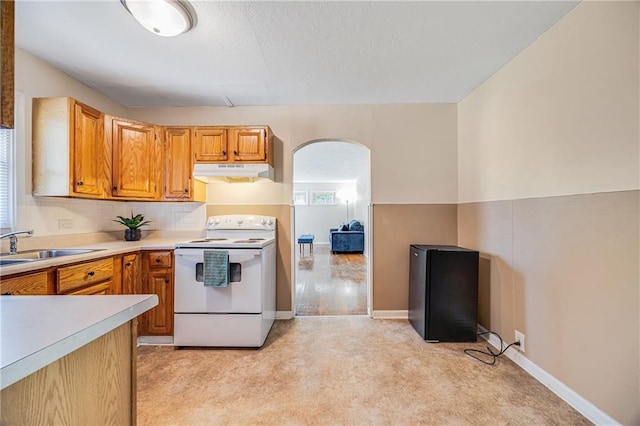 6132 N Eugene Field Rd, Kansas City, MO 64119 - kitchen featuring white range with electric stovetop, under cabinet range hood, arched walkways, light countertops, and light carpet