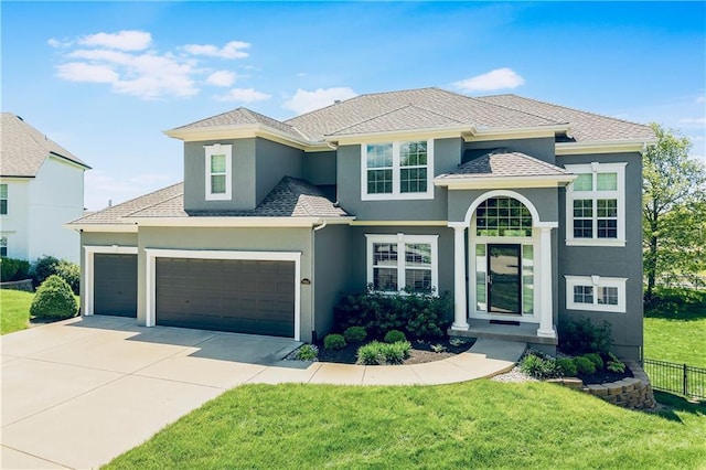 view of front of property with fence, concrete driveway, a garage, stucco siding, and a front yard