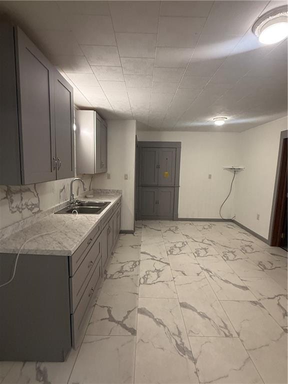 112 N Burns St N, Independence, KS 67301 - kitchen with a sink, gray cabinets, light marble finish floors, baseboards, and light countertops