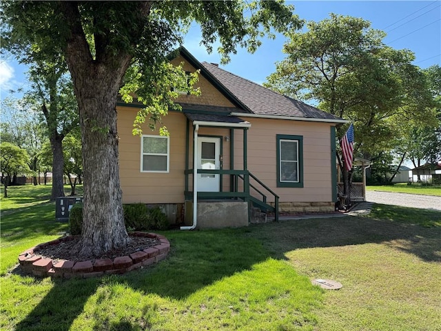112 N Burns St N, Independence, KS 67301 - bungalow with a front lawn, roof with shingles, and cooling unit