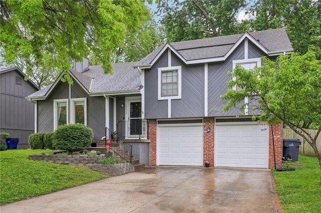tri-level home featuring roof with shingles, driveway, an attached garage, and a front yard