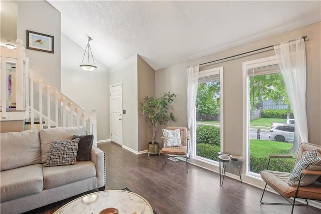 living area with vaulted ceiling, wood finished floors, stairs, and baseboards