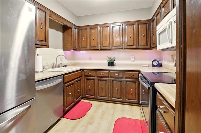 802 High Dr, Excelsior Springs, MO 64024 - kitchen featuring stainless steel appliances, light wood-style flooring, backsplash, a sink, and light countertops