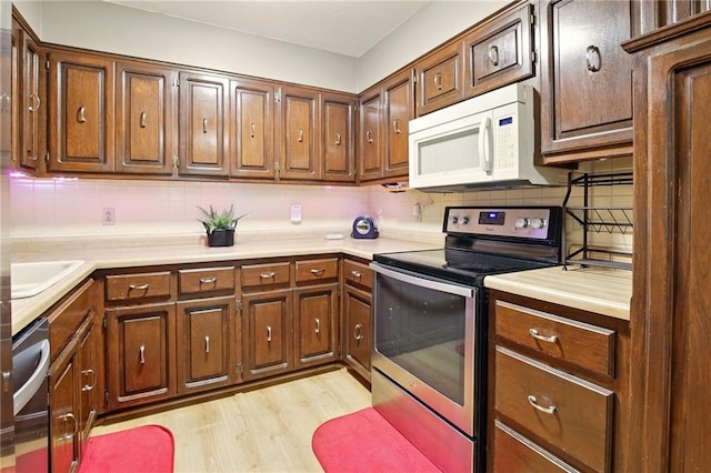 802 High Dr, Excelsior Springs, MO 64024 - kitchen featuring stainless steel range with electric cooktop, white microwave, tasteful backsplash, light wood-style floors, and light countertops